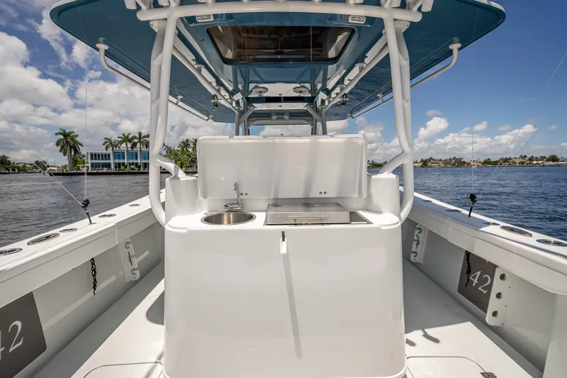 Slide: The Image of 2025 Yellowfin 42 Offshore boat interior with sink and grill, under blue sky. - 52