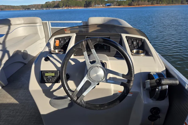 Slide: The Image of 2023 Bennington 22 SSR boat dashboard with steering wheel, controls, and lake view. - 10