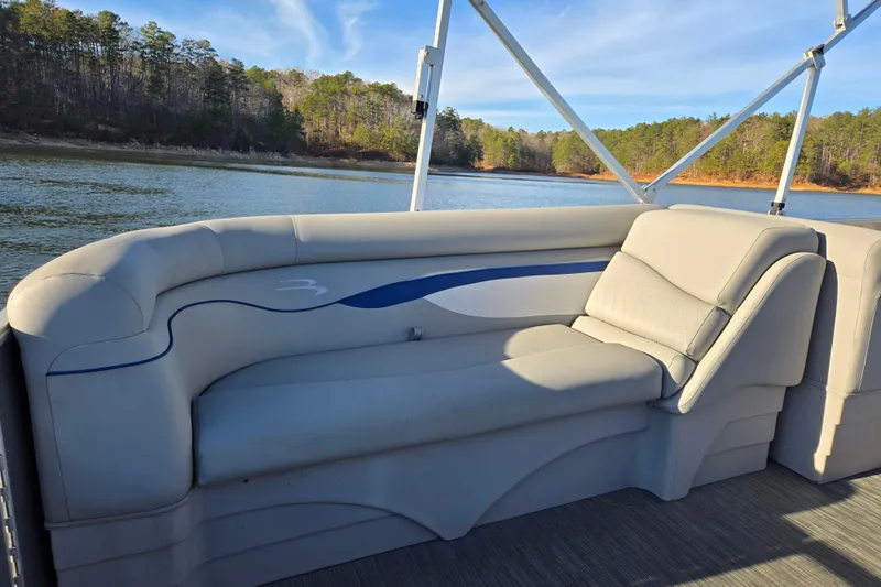 Slide: The Image of 2023 Bennington 22 SSR pontoon boat interior with comfortable seating by a scenic lake. - 16