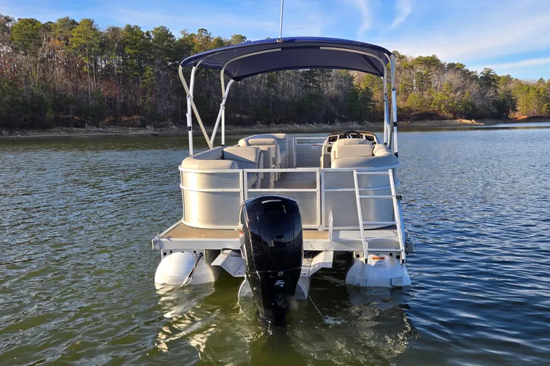 Slide: The Image of 2023 Bennington 22 SSR pontoon boat on a serene lake with forested shoreline. - 3
