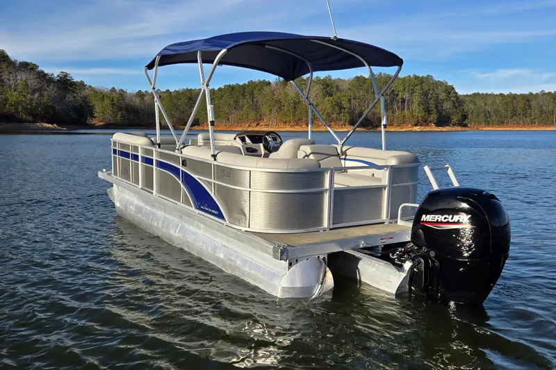 Slide: The Image of 2023 Bennington 22 SSR pontoon boat on a serene lake with forested shoreline. - 4