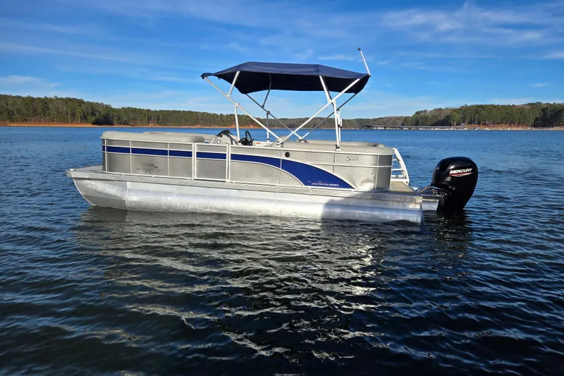 Slide: The Image of 2023 Bennington 22 SSR pontoon boat on a serene lake with a blue canopy. - 5