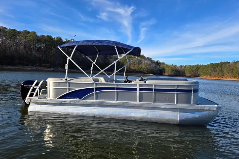 Slide: The Image of 2023 Bennington 22 SSR pontoon boat on a serene lake with blue sky backdrop. - 8