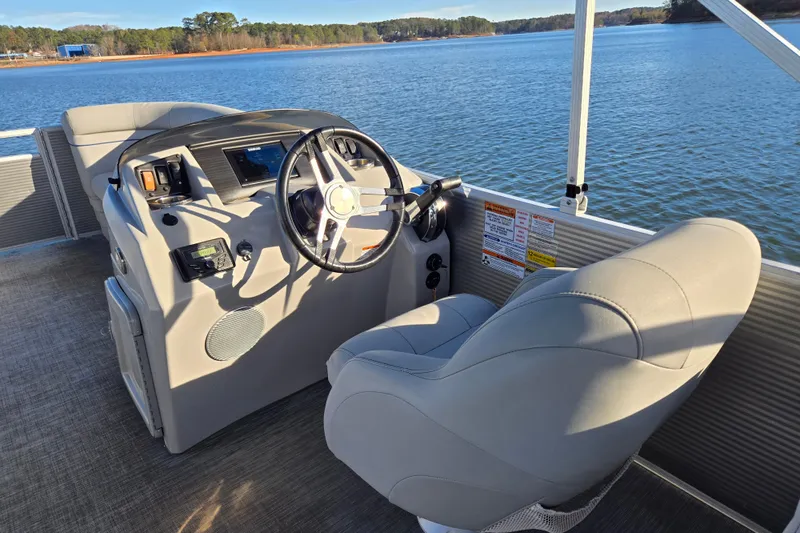 Slide: The Image of 2023 Bennington 22 SSR boat interior with steering wheel and captain's chair on a lake. - 9