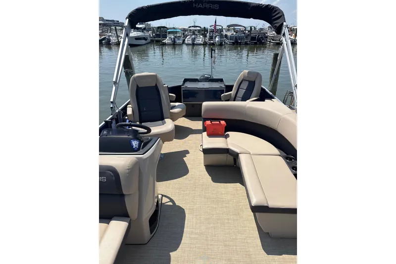 Slide: The Image of 2025 Harris Cruiser 230 pontoon boat interior with beige seating at marina. - 5