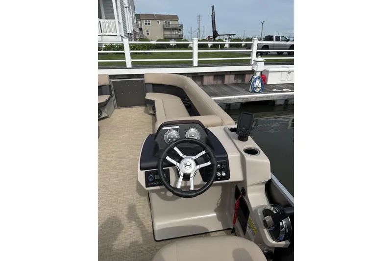 Slide: The Image of 2025 Harris Cruiser 230 boat interior with steering wheel and dashboard at dock. - 8