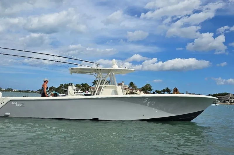 The Image of 2018 SeaVee 390Z boat on water, clear sky, people onboard, coastal background. - 0