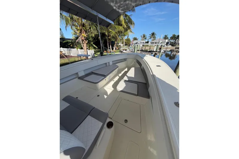 Slide: The Image of 2018 SeaVee 390Z boat interior with cushioned seating, docked near palm trees. - 12