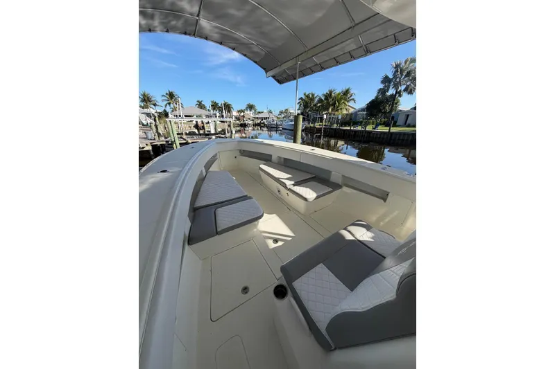 Slide: The Image of 2018 SeaVee 390Z boat interior with seating, docked by palm trees and calm water. - 5