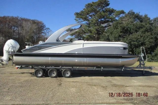Slide: The Image of 2022 Bennington RX Sport Line boat on trailer, parked outdoors under clear blue sky. - 0
