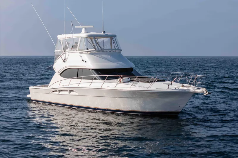 Slide: The Image of 2005 Riviera 47 Convertible yacht cruising on open sea under clear sky. - 12