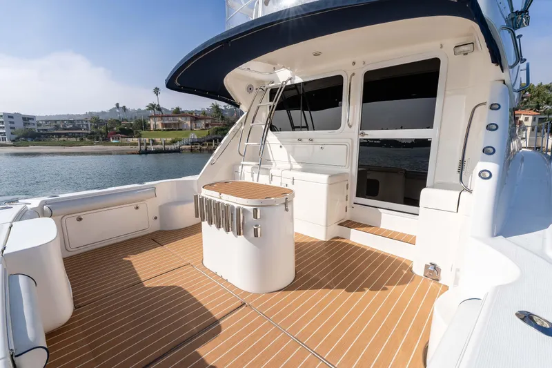 Slide: The Image of 2005 Riviera 47 Convertible yacht deck with teak flooring, docked by waterfront homes. - 16