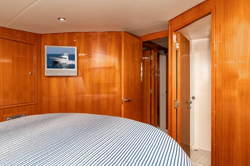 Slide: The Image of Interior of 2005 Riviera 47 Convertible yacht with wood paneling and striped bedding. - 31