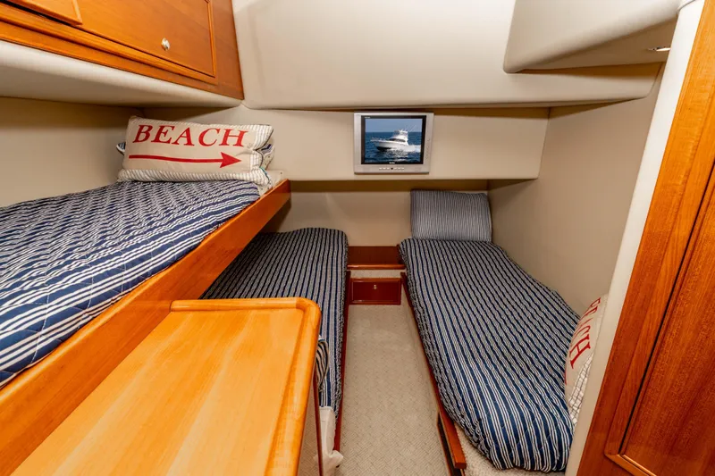Slide: The Image of 2005 Riviera 47 Convertible cabin with striped bedding and nautical decor. - 38