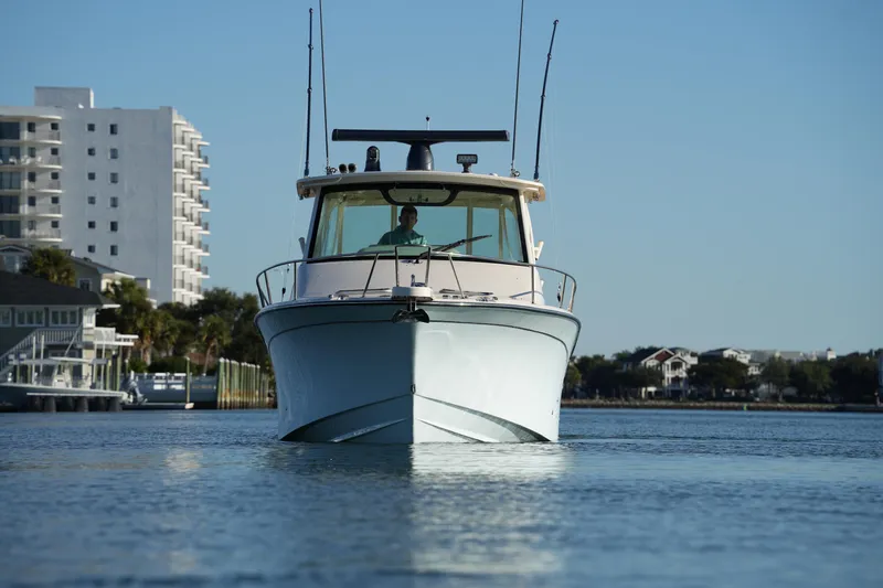 Slide: The Image of 2024 Grady-White Express 330 boat on calm water near urban buildings. - 10