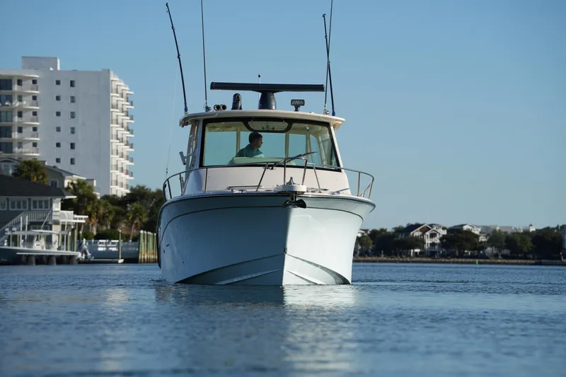 Slide: The Image of 2024 Grady-White Express 330 boat cruising on calm waters near coastal buildings. - 11