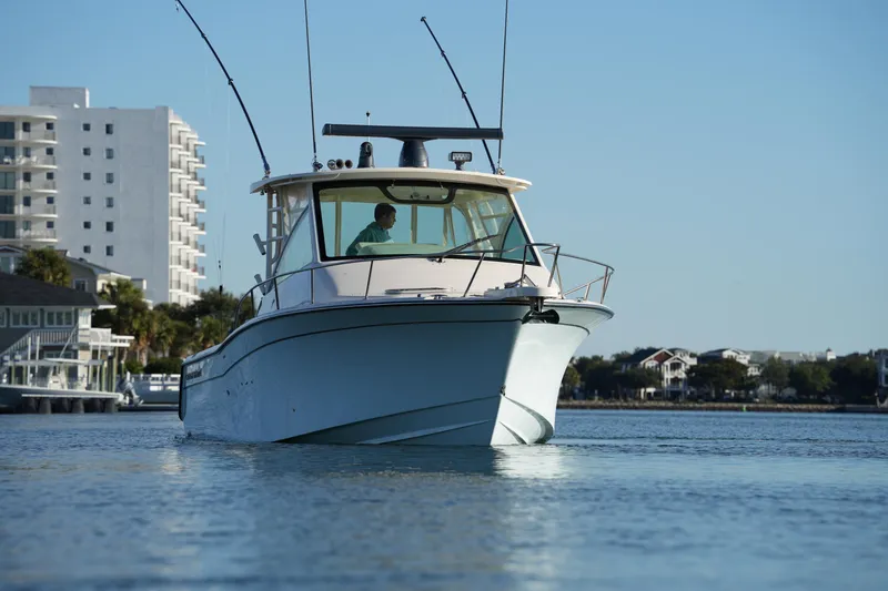 Slide: The Image of 2024 Grady-White Express 330 boat cruising near waterfront buildings. - 12