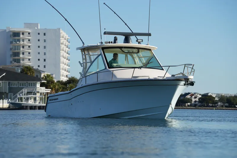 Slide: The Image of 2024 Grady-White Express 330 boat cruising near waterfront buildings. - 13