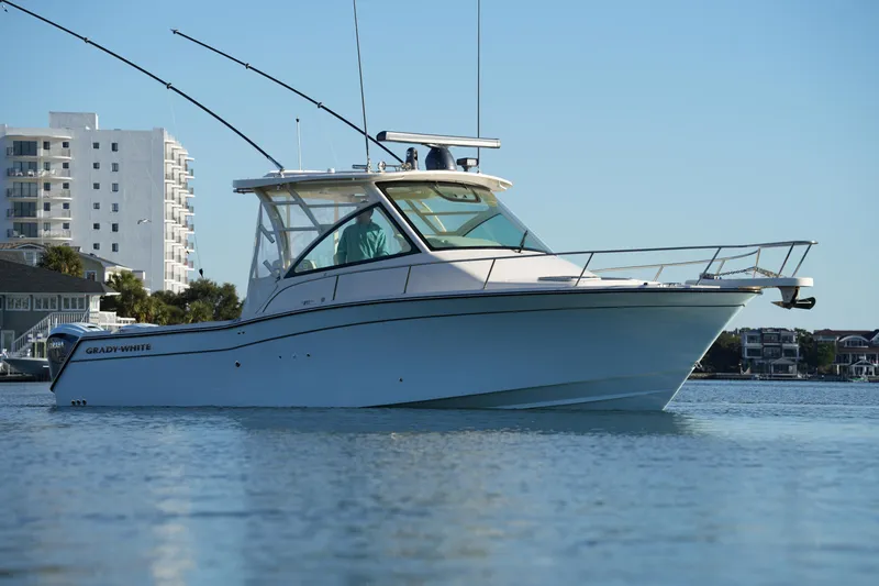 Slide: The Image of 2024 Grady-White Express 330 boat on calm water with cityscape background. - 15
