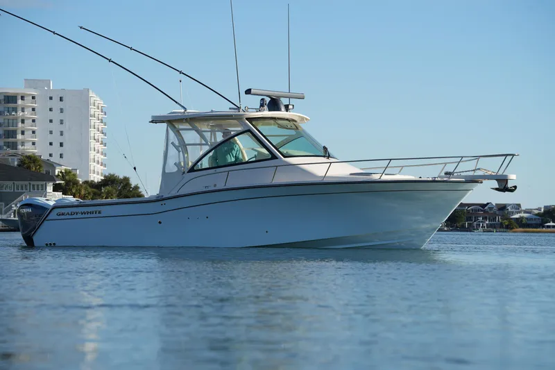 Slide: The Image of 2024 Grady-White Express 330 boat on calm water, with cityscape background. - 16