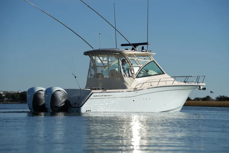 Slide: The Image of 2024 Grady-White Express 330 boat on calm water, featuring dual outboard engines. - 23