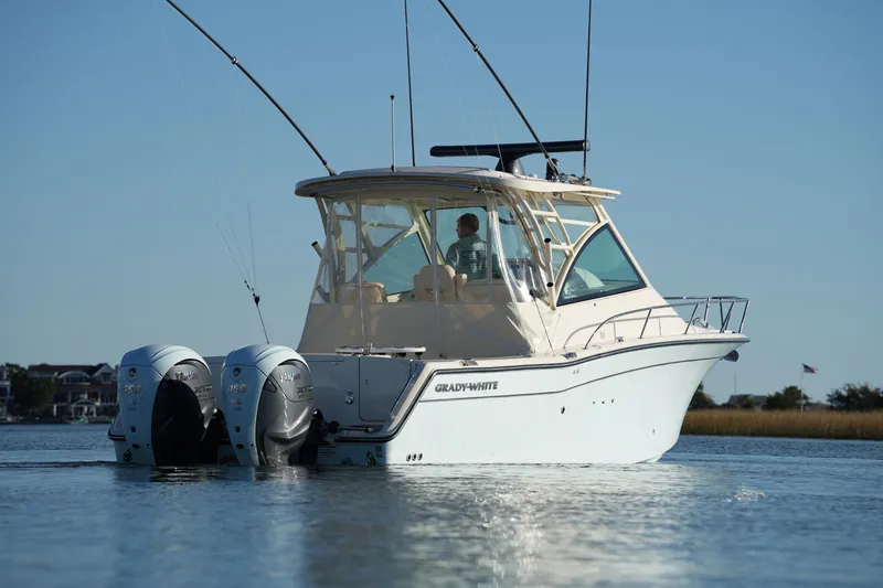 Slide: The Image of 2024 Grady-White Express 330 boat on calm water, featuring dual outboard engines. - 25