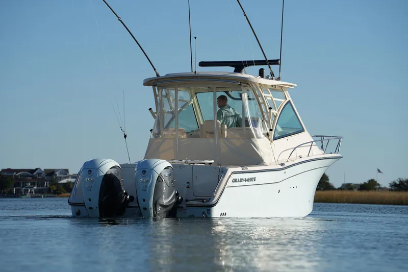 Slide: The Image of 2024 Grady-White Express 330 boat on calm water, featuring dual outboard engines. - 26