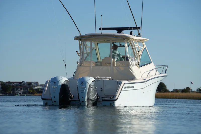 Slide: The Image of 2024 Grady-White Express 330 boat on calm water, rear view with dual engines. - 28