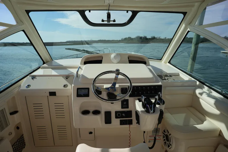 Slide: The Image of 2024 Grady-White Express 330 helm with steering wheel and controls, overlooking water. - 49