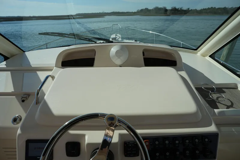 Slide: The Image of 2024 Grady-White Express 330 helm with steering wheel and control panel, overlooking water. - 56