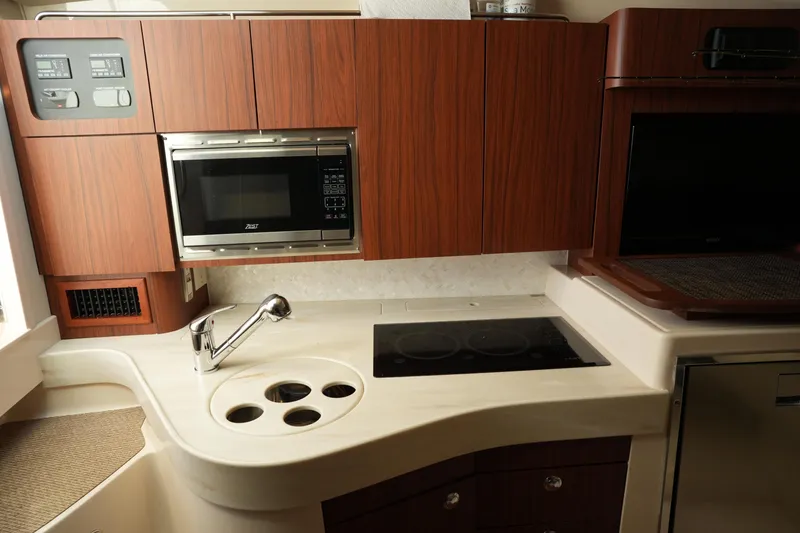 Slide: The Image of 2024 Grady-White Express 330 kitchen with microwave, stove, and wooden cabinetry. - 60