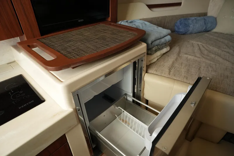 Slide: The Image of 2024 Grady-White Express 330 interior with open fridge and cozy seating area. - 64