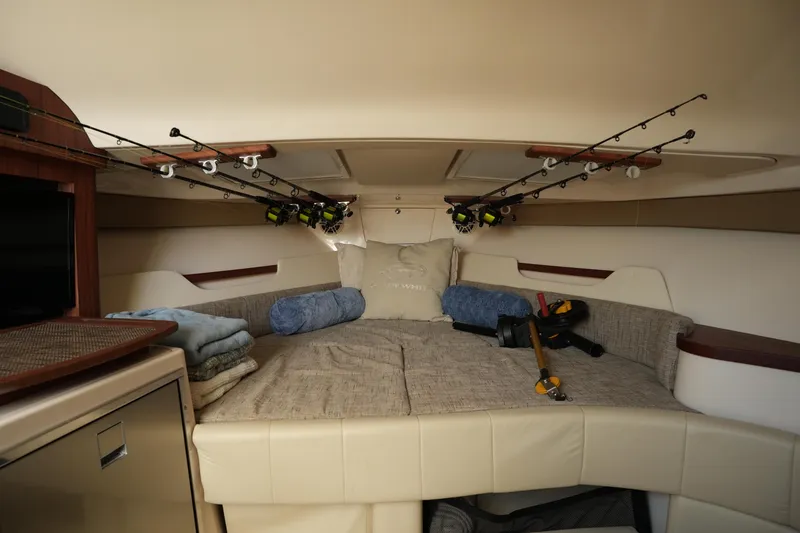 Slide: The Image of 2024 Grady-White Express 330 cabin interior with fishing rods and cozy bedding. - 65
