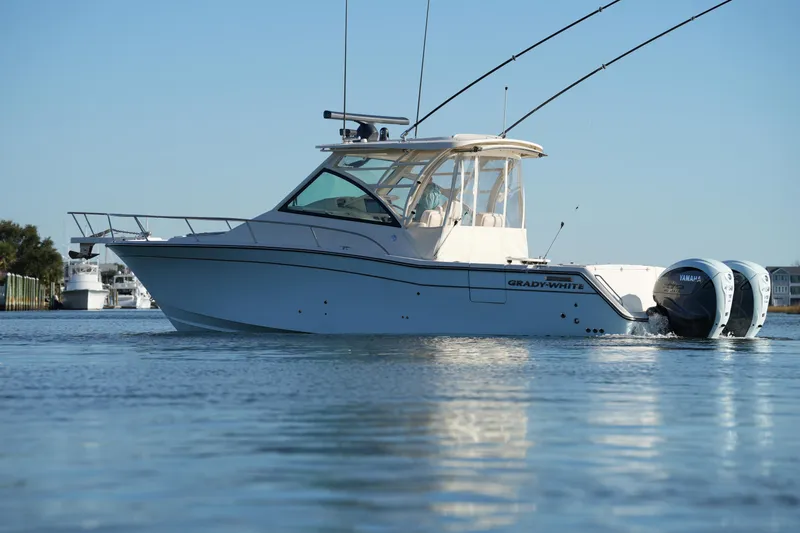 Slide: The Image of 2024 Grady-White Express 330 boat on calm water, featuring twin Yamaha engines. - 8