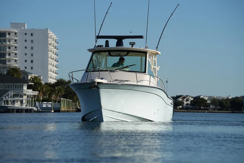 Slide: The Image of 2024 Grady-White Express 330 boat cruising on calm water near coastal buildings. - 9