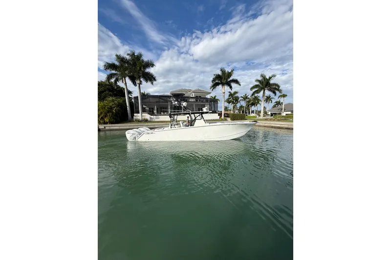 Slide: The Image of 2020 SeaHunter 41 CTS boat docked near a waterfront home with palm trees. - 2