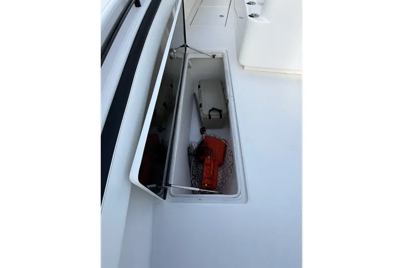 Slide: The Image of 2020 SeaHunter 41 CTS boat interior with open storage compartments, docked by waterfront homes. - 27