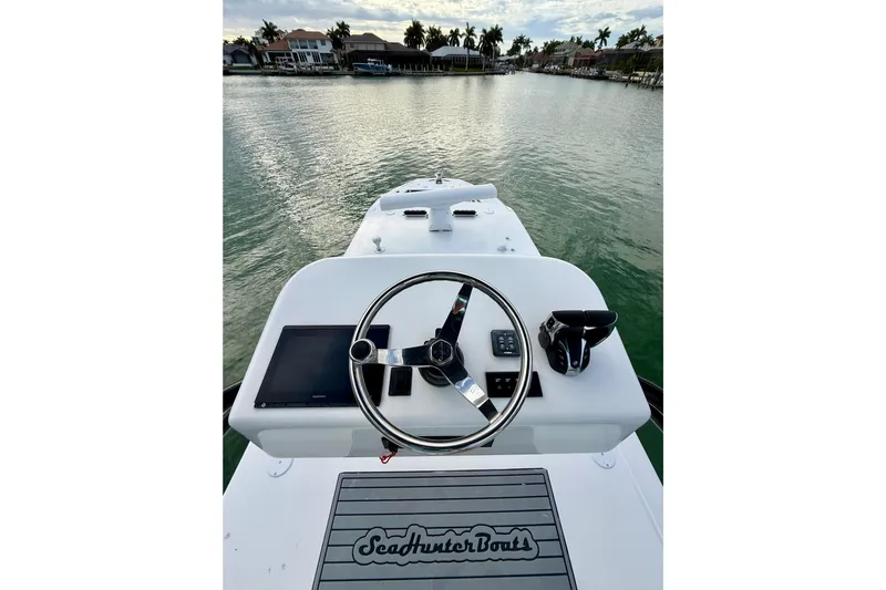 Slide: The Image of 2020 SeaHunter 41 CTS boat helm with steering wheel and controls on calm water. - 50