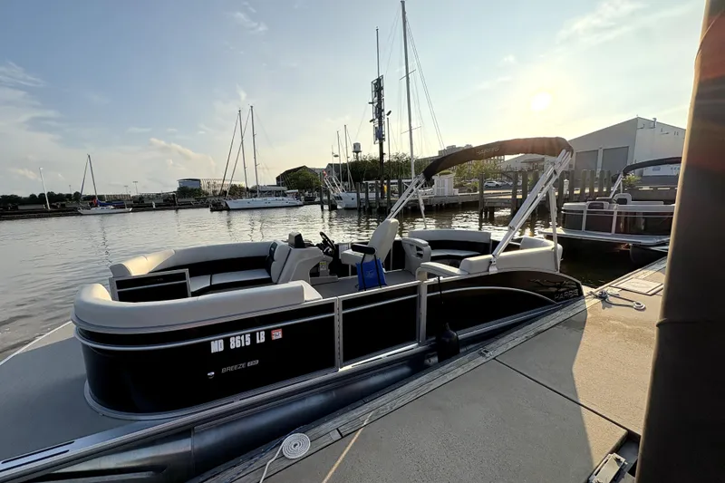 The Image of 2025 Harris Breeze 230 pontoon boat docked at marina during sunset. - 1