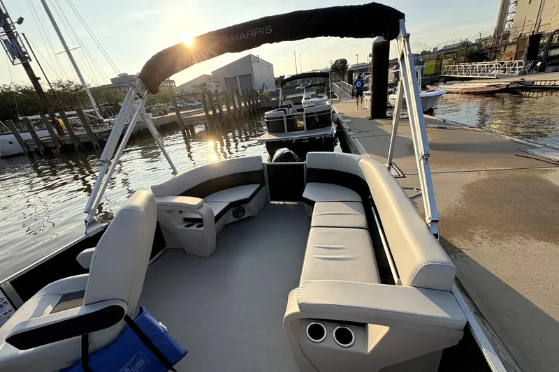 Slide: The Image of 2025 Harris Breeze 230 pontoon boat docked at sunset, featuring spacious seating and canopy. - 4