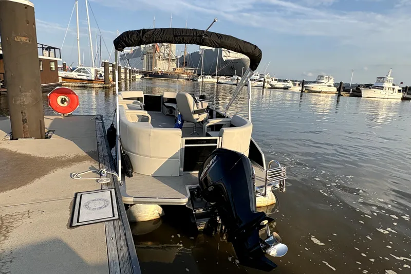 Slide: The Image of 2025 Harris Breeze 230 pontoon boat docked at marina with other boats. - 5