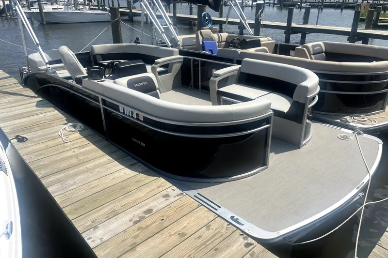 The Image of 2025 Harris Breeze 230 pontoon boat docked at marina, featuring sleek design and spacious seating. - 1