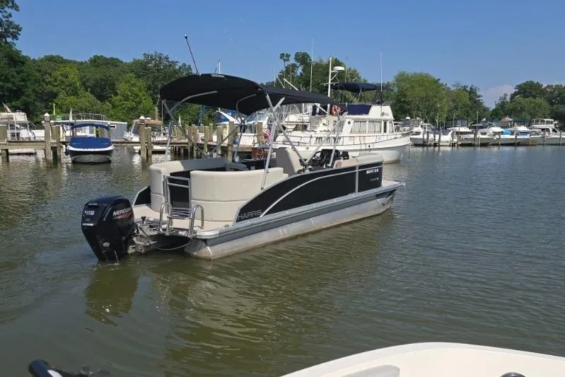 Slide: The Image of 2025 Harris Breeze 230 pontoon boat docked in a marina under clear blue skies. - 3