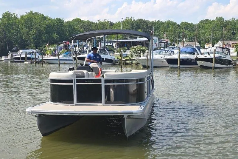 Slide: The Image of 2025 Harris Breeze 230 pontoon boat on a calm lake near a marina. - 7