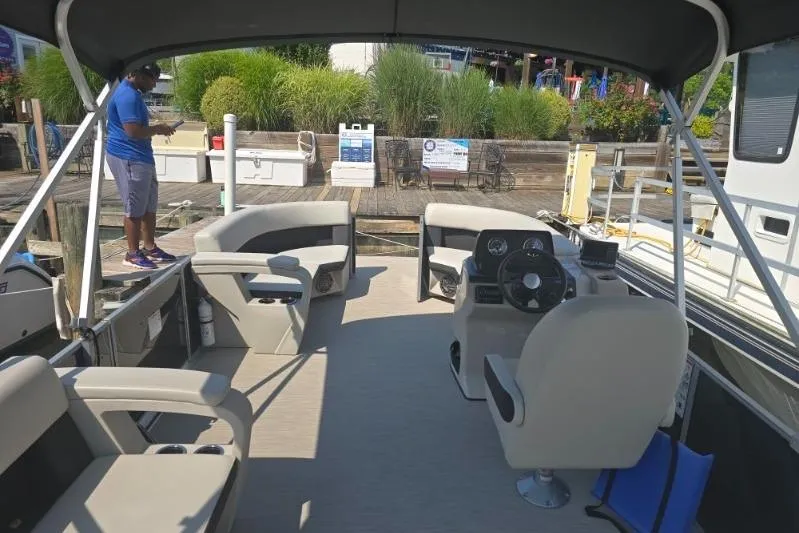 Slide: The Image of 2025 Harris Breeze 230 pontoon boat interior with seating and steering console. - 8