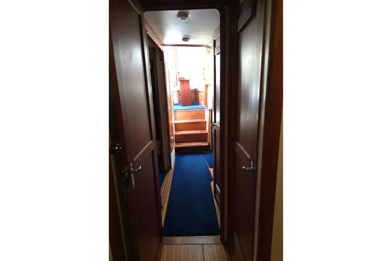 Slide: The Image of Interior hallway of 2004 Legacy Yachts Sedan Flybridge with blue carpet and wooden doors. - 12