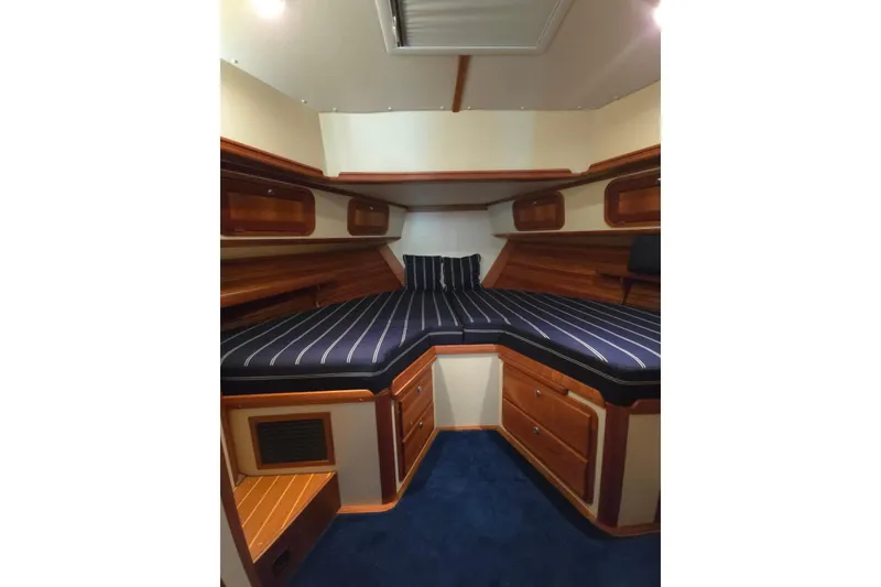 Slide: The Image of Luxurious 2004 Legacy Yachts Sedan Flybridge cabin with striped bedding and wooden accents. - 13