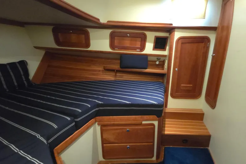 Slide: The Image of 2004 Legacy Yachts Sedan Flybridge cabin with striped bedding and wooden interior. - 14