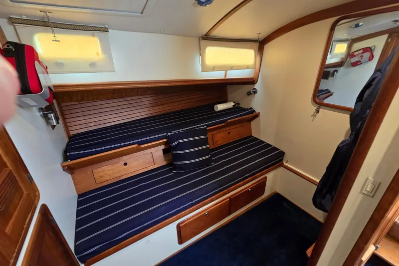 Slide: The Image of 2004 Legacy Yachts Sedan Flybridge cabin with striped bedding and wooden accents. - 15