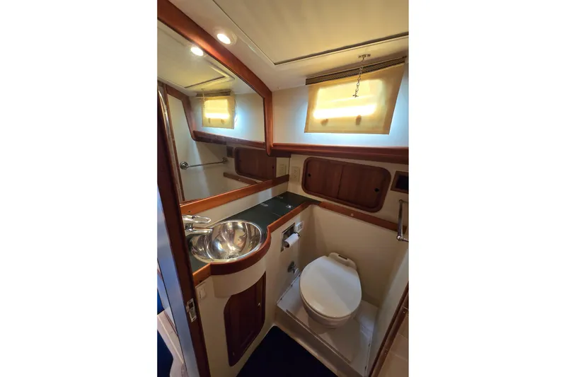 Slide: The Image of 2004 Legacy Yachts Sedan Flybridge bathroom with sink, toilet, and wooden accents. - 17